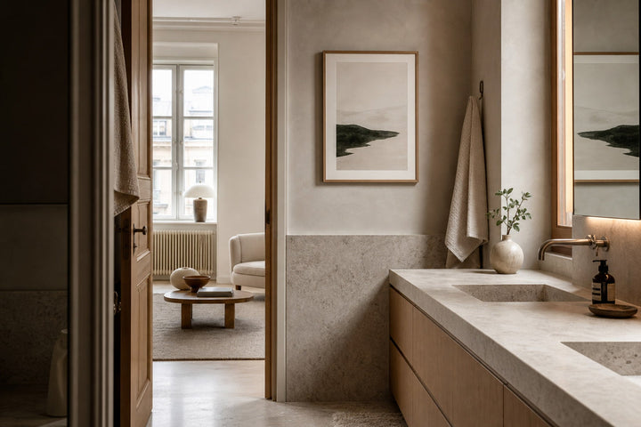 Nordic editorial spa-like Nordic bathroom featuring calming framed art placed on a dry wall above pale stone and oak cabinetry