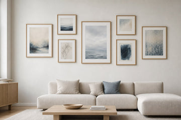 Nordic editorial living room featuring professionally hung, balanced gallery wall of five to seven varied framed artworks with precise spacing