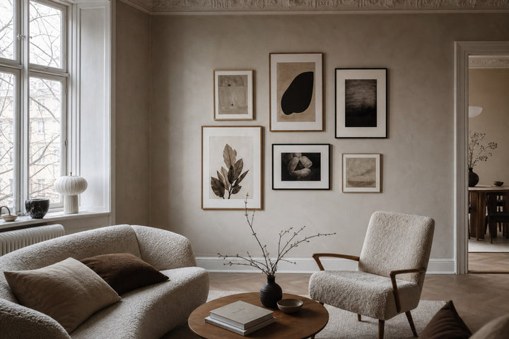 Nordic editorial living room featuring professionally hung, balanced gallery wall of five to seven varied framed artworks with precise spacing